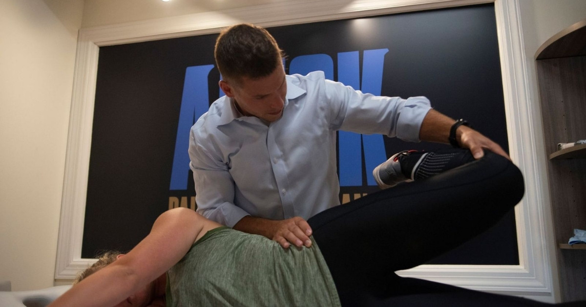 Chiropractor Helping Patient Stretch Lower Body